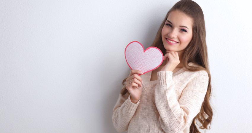 Portrait of beautiful happy woman holding a symbol heart.
